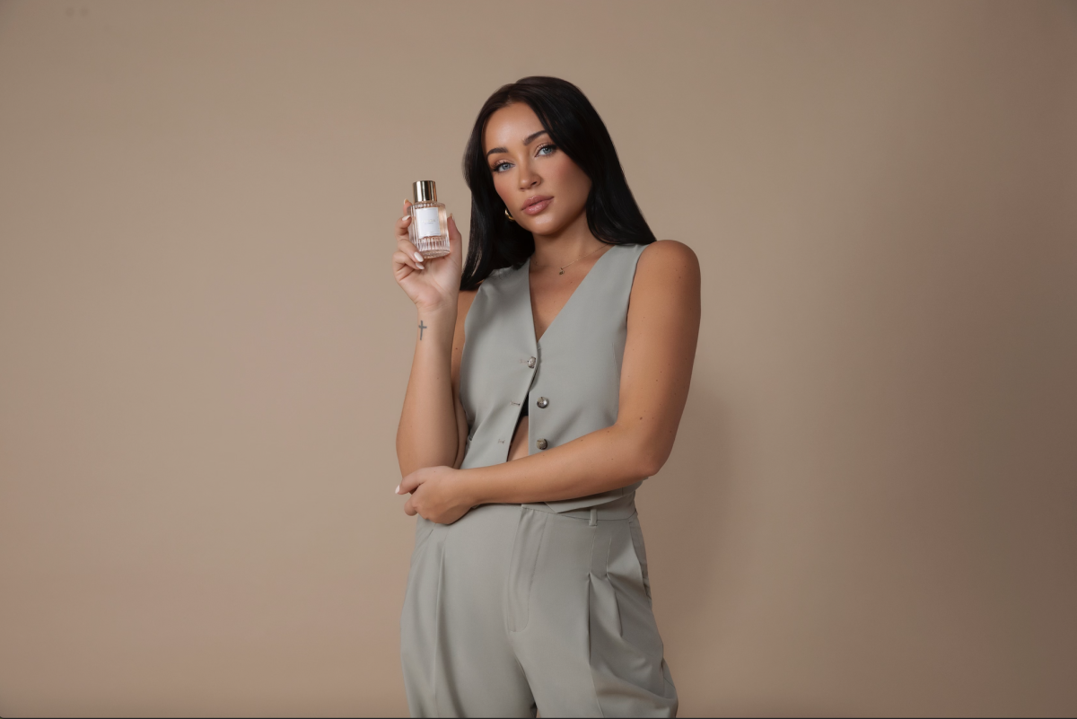 A woman poses with a bottle of perfume.
