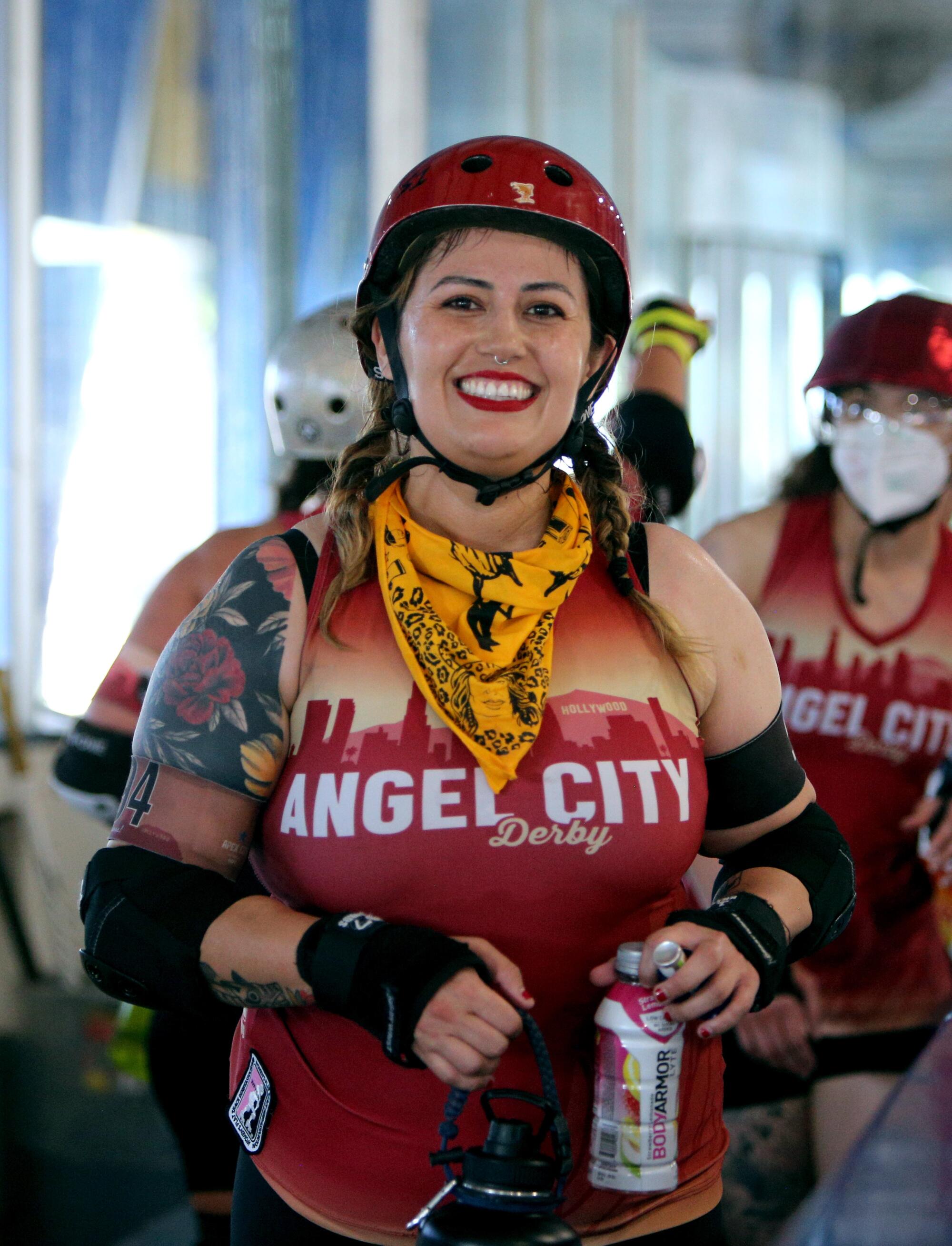 A woman wearing a helmet and elbow and wrist pads smiling