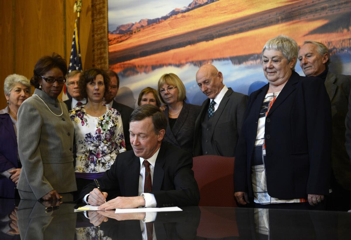 Colorado Gov. John Hickenlooper signs gun control measures in his office at the state Capitol in Denver.