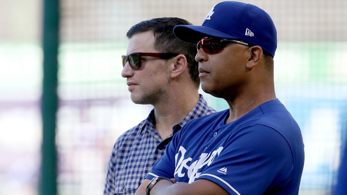 Andrew Friedman and manager Dave Roberts watch Dodgers players warm up for a game earlier this season.