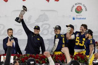 Michigan coach Jim Harbaugh holds the Rose Bowl trophy after the Wolverines' win over Alabama.