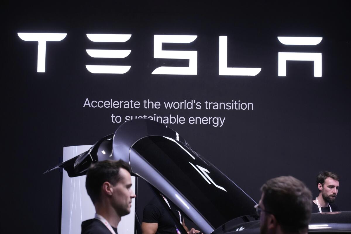 People walk past a Model Y is seen at a Tesla stand