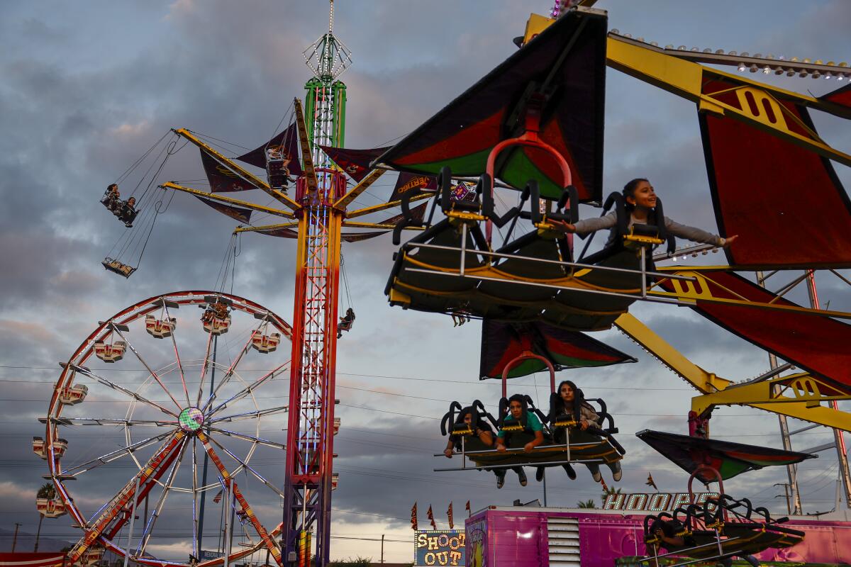 People on carnival rides against a partly cloudy sky