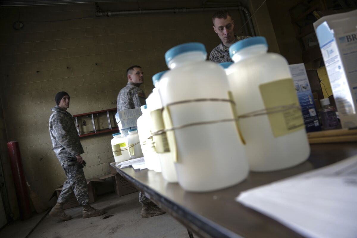 FILE - In this Jan. 18, 2016 file photo, water analysis test kits for Flint, Mich., residents to pick up for lead testing in their drinking water are set out on a table at Flint Fire Department Station No. 1 as members of the U.S. Army National Guard 125th Infantry Battalion wait to help residents. Flint has taken important steps toward resolving the lead contamination crisis that made the impoverished Michigan city a symbol of the drinking water problems that plague many U.S. communities, officials said Monday, Dec. 7, 2020. (Ryan Garza/Detroit Free Press via AP, File)