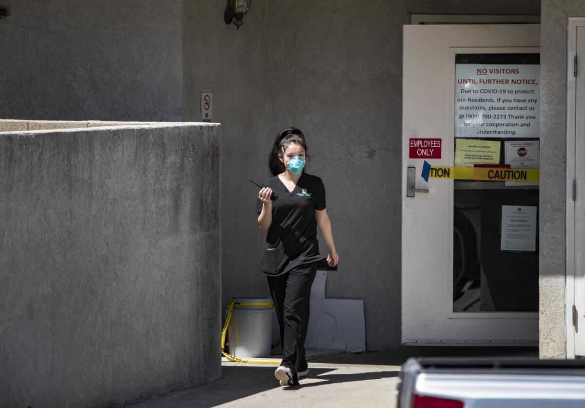 An employee exits Cedar Mountain Post Acute nursing home where 51 residents and 6 staff members have tested positive for coronavirus in Yucaipa, Calif. Two residents have died.