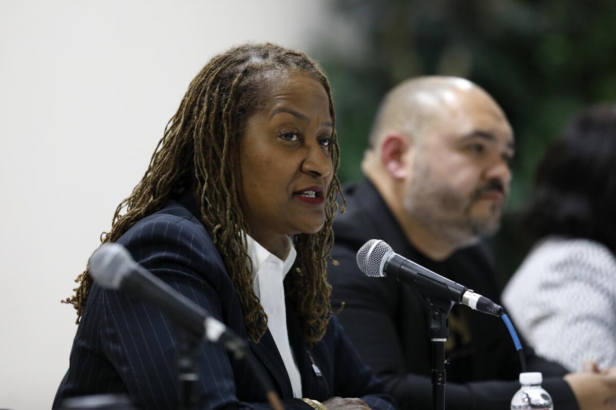 Supervisor Holly Mitchell sits at a table, speaking into a microphone