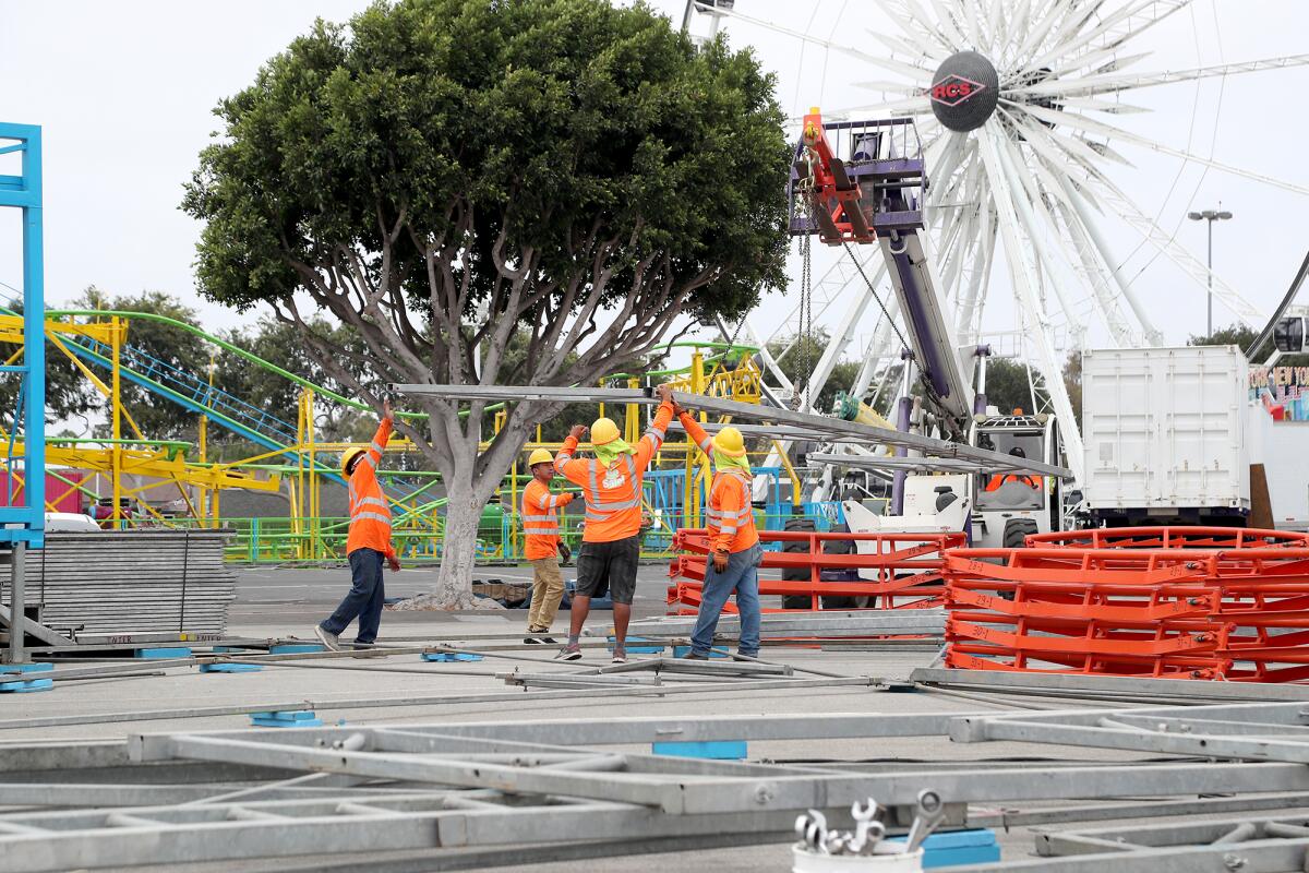 RCS carnival workers set up a ride as preparations for the 2021 O.C. Fair take place on Tuesday in Costa Mesa.