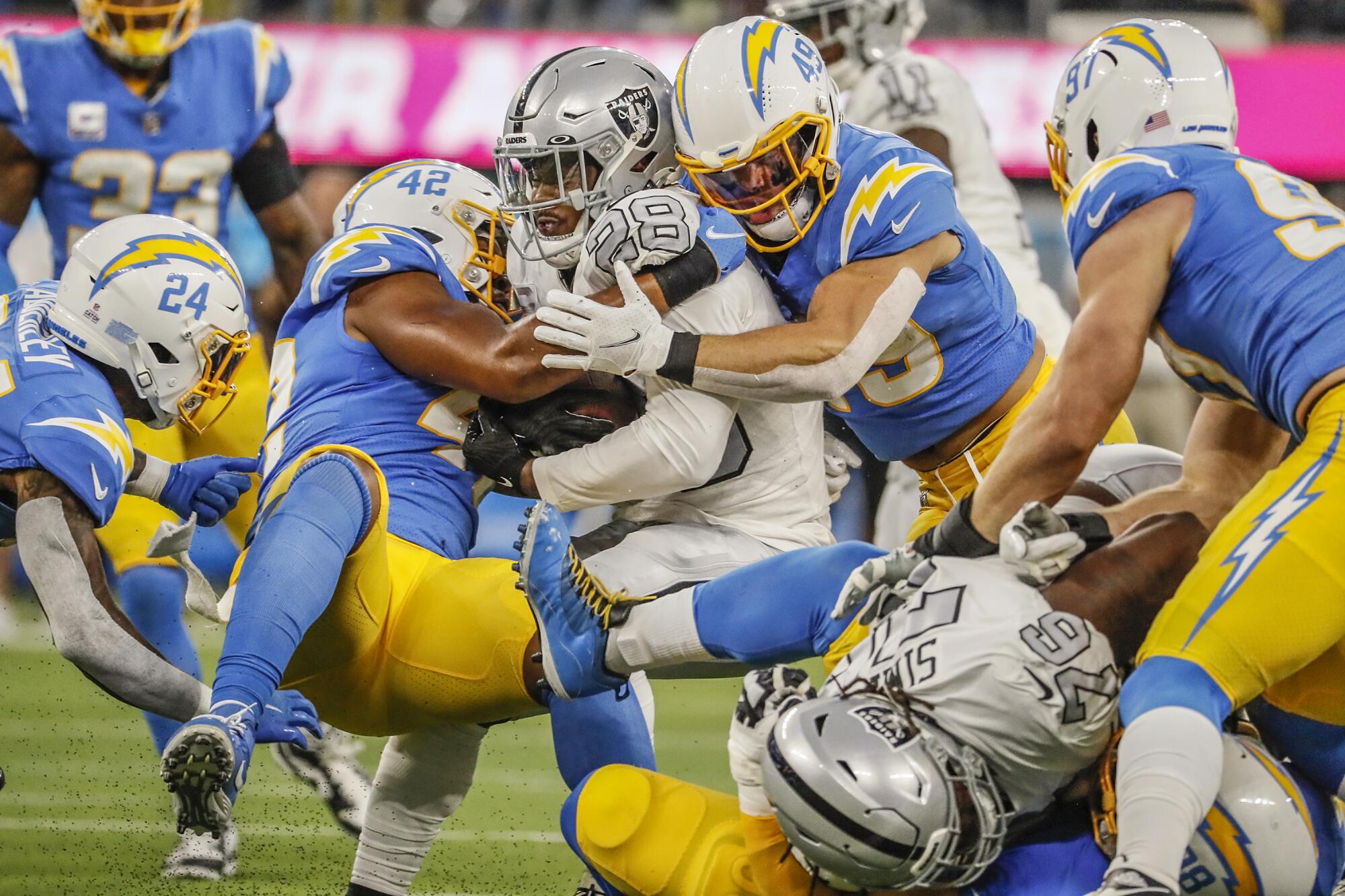 Las Vegas Raiders running back Josh Jacobs is sandwiched by Los Angeles Chargers linebacker Drue Tranquill and Uchenna Nwosu