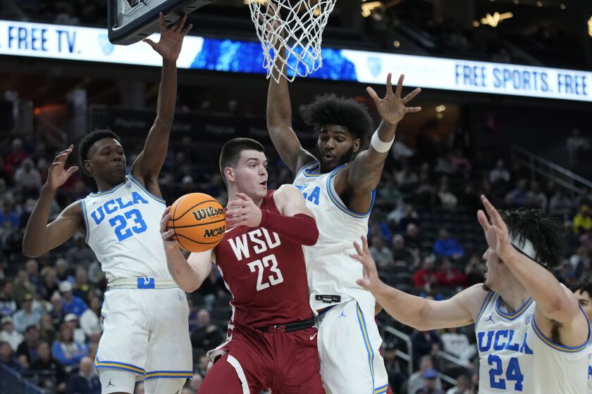 Washington State's Andrej Jakimovski (23) passes around UCLA players during the first half of an NCAA college basketball game in the quarterfinal round of the Pac-12 tournament Thursday, March 10, 2022, in Las Vegas. (AP Photo/John Locher)