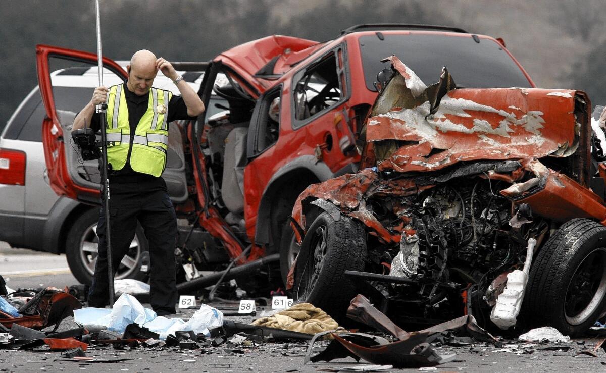 Steve Taggart, left, of the California Highway Patrol, takes measurements at the wreckage of a car crash on the westbound 60 Freeway in Diamond Bar. A wrong-way driver in a Camaro (the very smashed car in front) crashed head-on with a Ford Explorer (middle red SUV) and a Ford Freestyle (silver SUV in back).