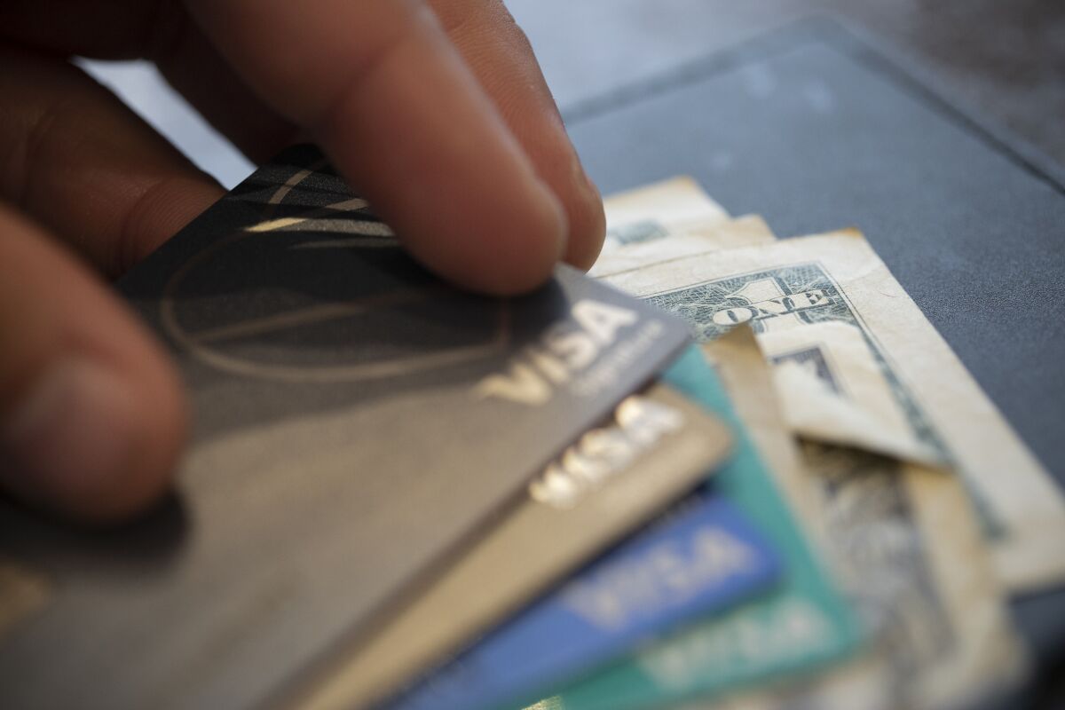  In this Aug. 11, 2019, file photo a man puts his Visa card on a stack of cards.