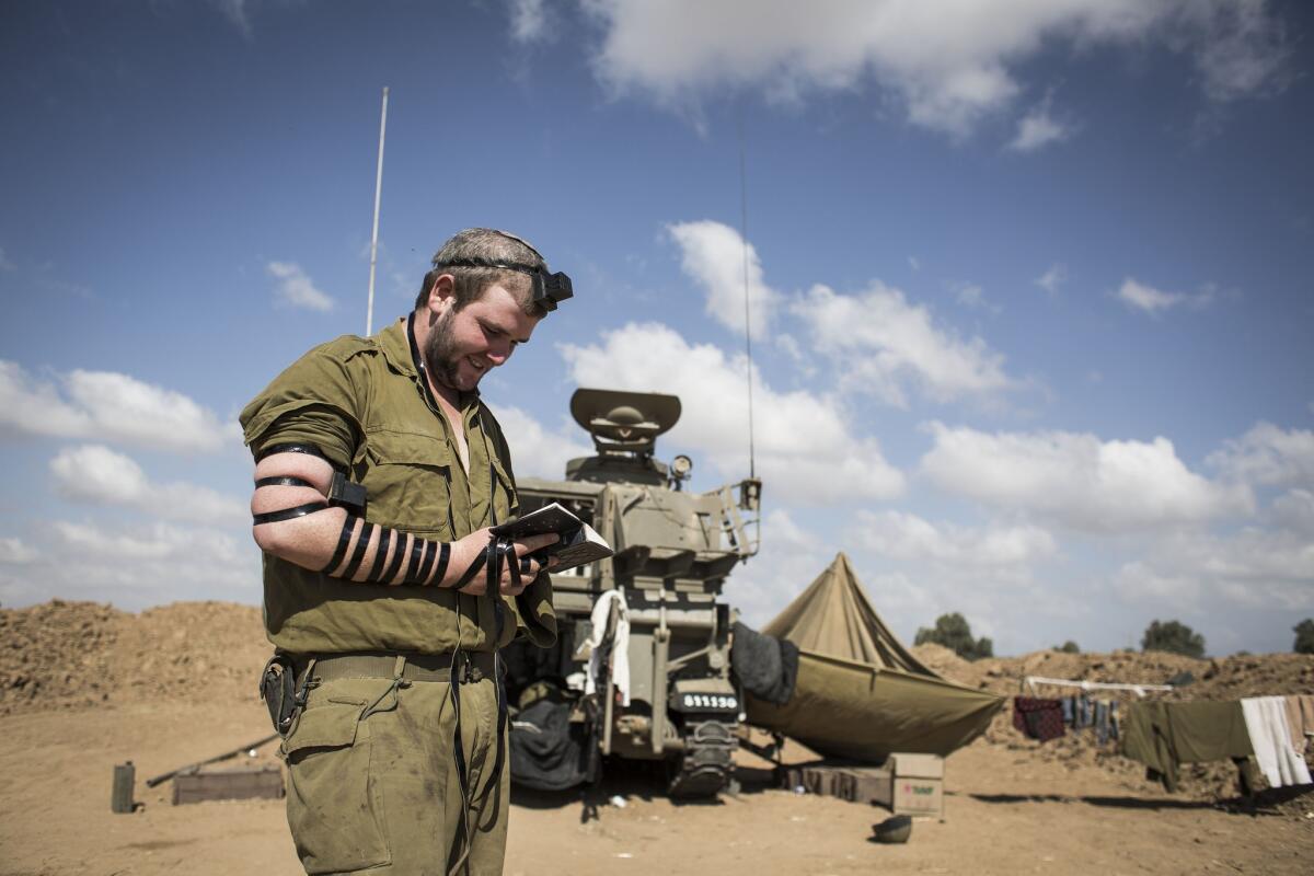 Israeli soldier seen praying by artillery cannon Wednesday at the Israeli-Gaza border.