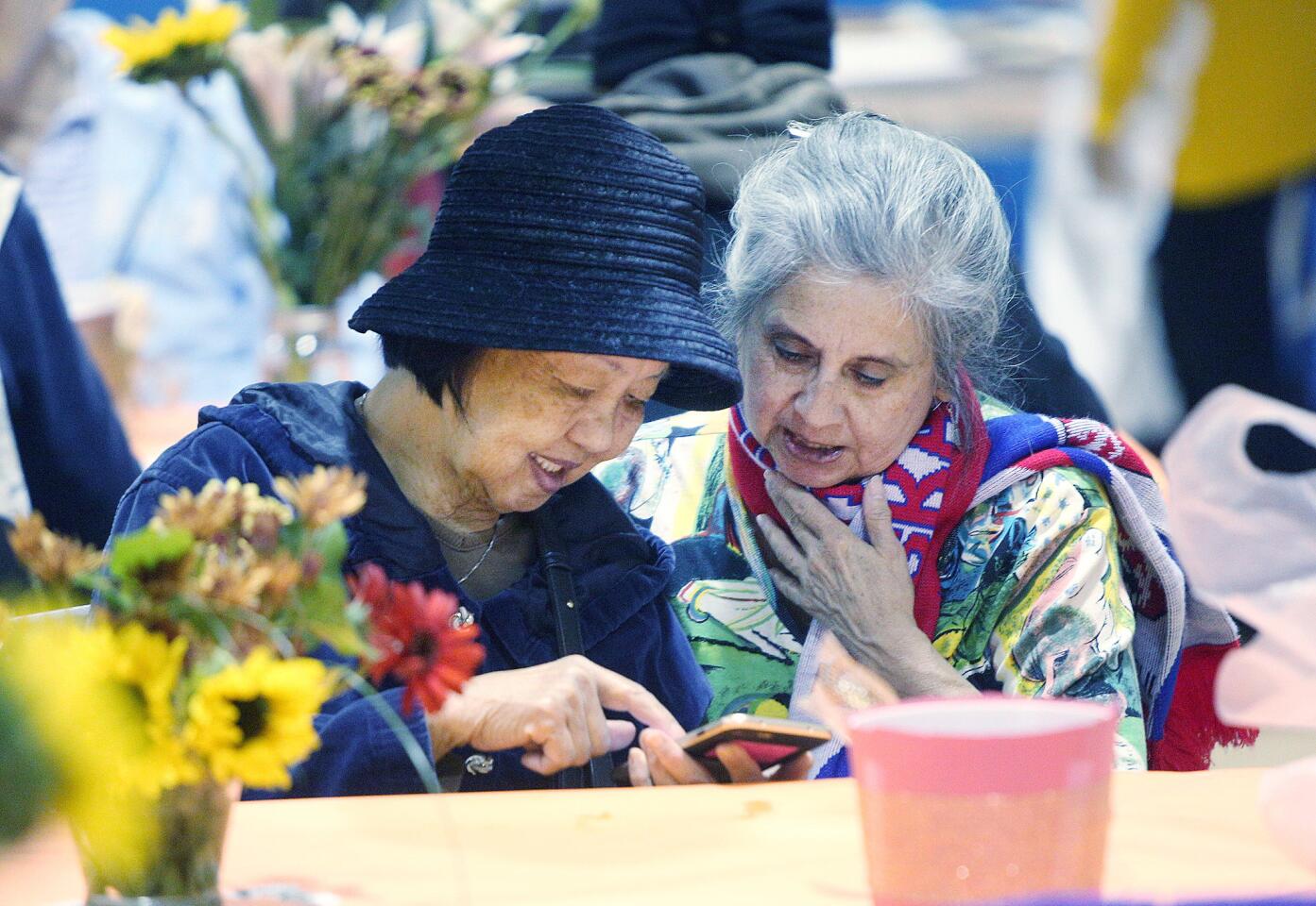 Linda Lin, of Glendale, shows Anita Black, of Glendale, her family photos on her cell phone at The Glendale Salvation Army for the annual Thanksgiving dinner on Tuesday, November 20, 2018. Black is a volunteer with a goal of meeting people, and was drawn to Lin who shared her family story with her.
