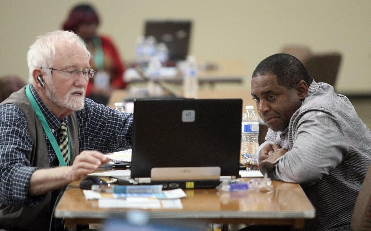 Insurance agent Mike Everding, left, helps James Randle enroll in Covered California coverage at a sign-up event last year in Inglewood.