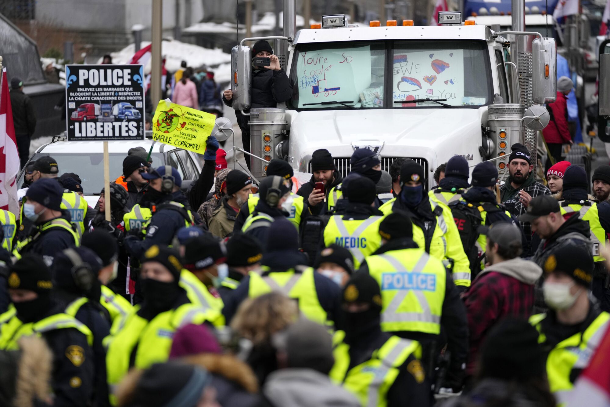 In a sea of yellow vests, some marked "police" or "medic," a protester records the authorities