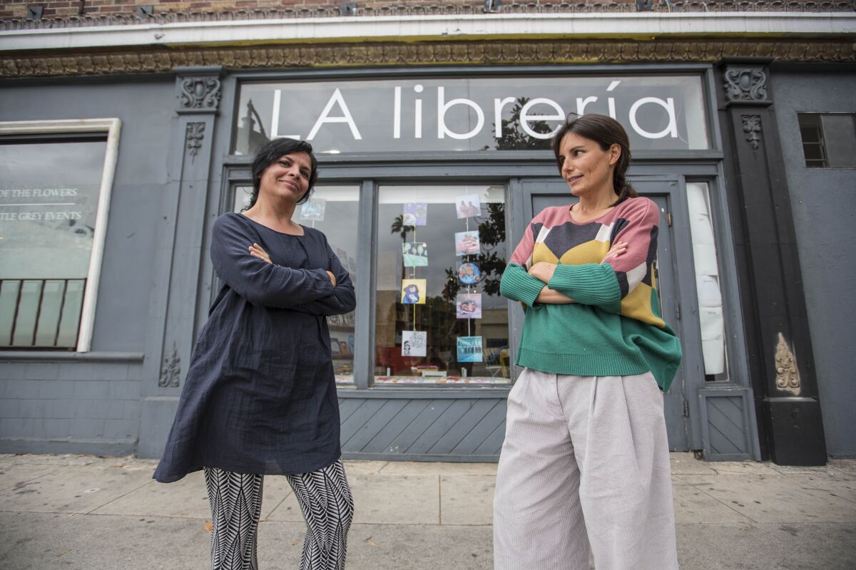 Celene Navarrete, left, and Chiara Arroyo in front of their LA Libreria bookstore in the Mid-City neighborhood. They have cut half their staff and used a loan to pay their rent during the state-ordered shutdown of most businesses.