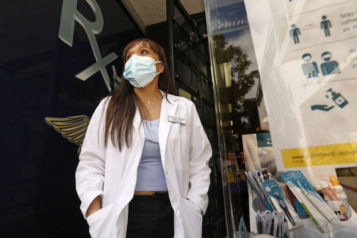 Hanh Duong, a pharmacist at Peninsula Pharmacy in San Pedro, wears a double mask when dealing with customers. 