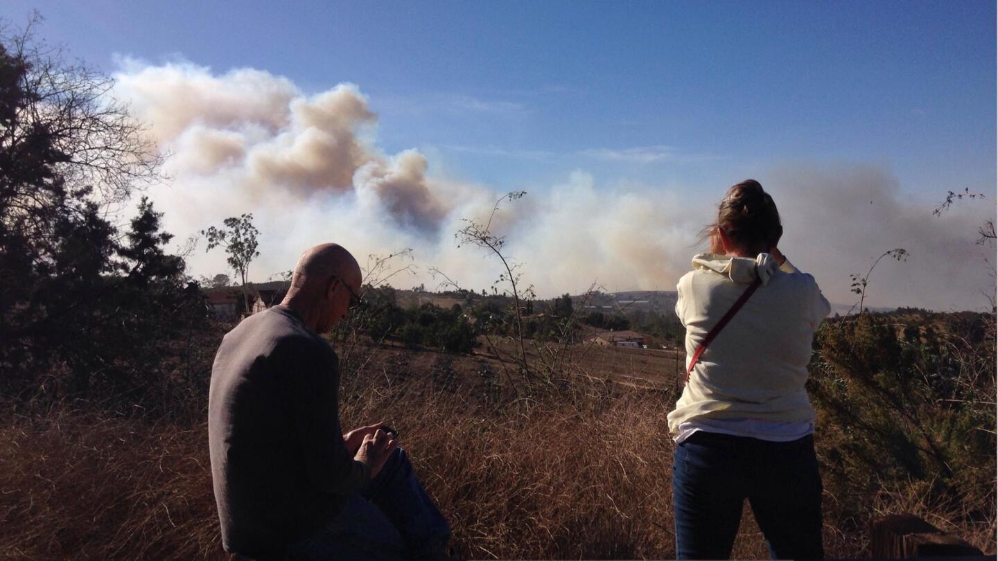 Spectators watch from Old Highway 395 as smoke rises from the Lilac Fire.
