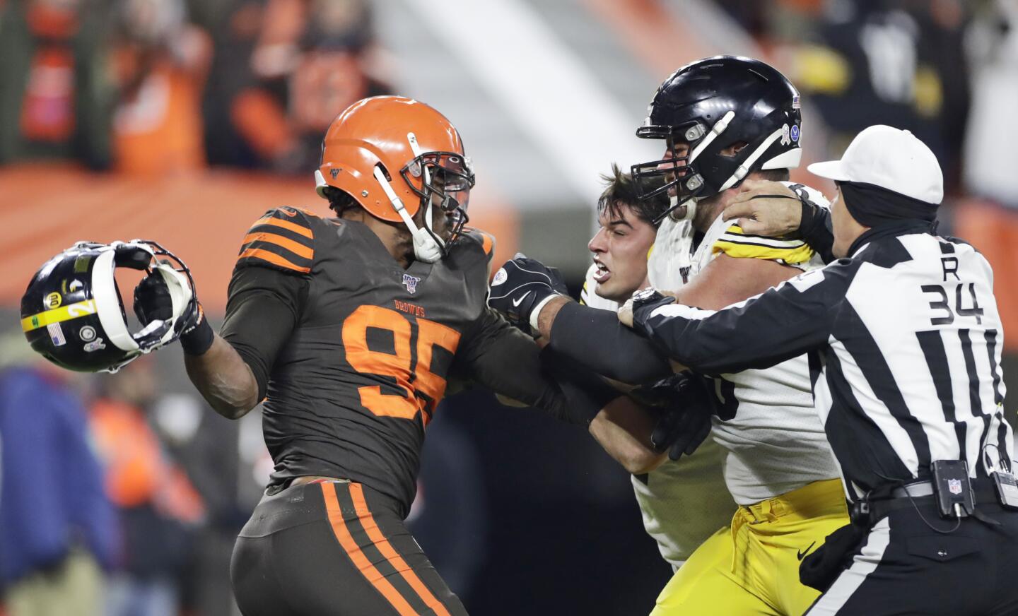 Cleveland Browns defensive end Myles Garrett, left, gets ready to hit Pittsburgh Steelers quarterback Mason Rudolph, second from left, with a helmet during the second half of an NFL football game Thursday, Nov. 14, 2019, in Cleveland. The Browns won 21-7. (AP Photo/Ron Schwane)