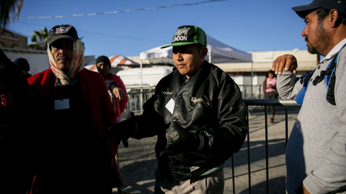 Jose Alexander, center, who took his 4-year-old son to the border wall and witnessed tear gas being fired early on New Year's Day, speaks to other migrants outside El Barretal shelter.