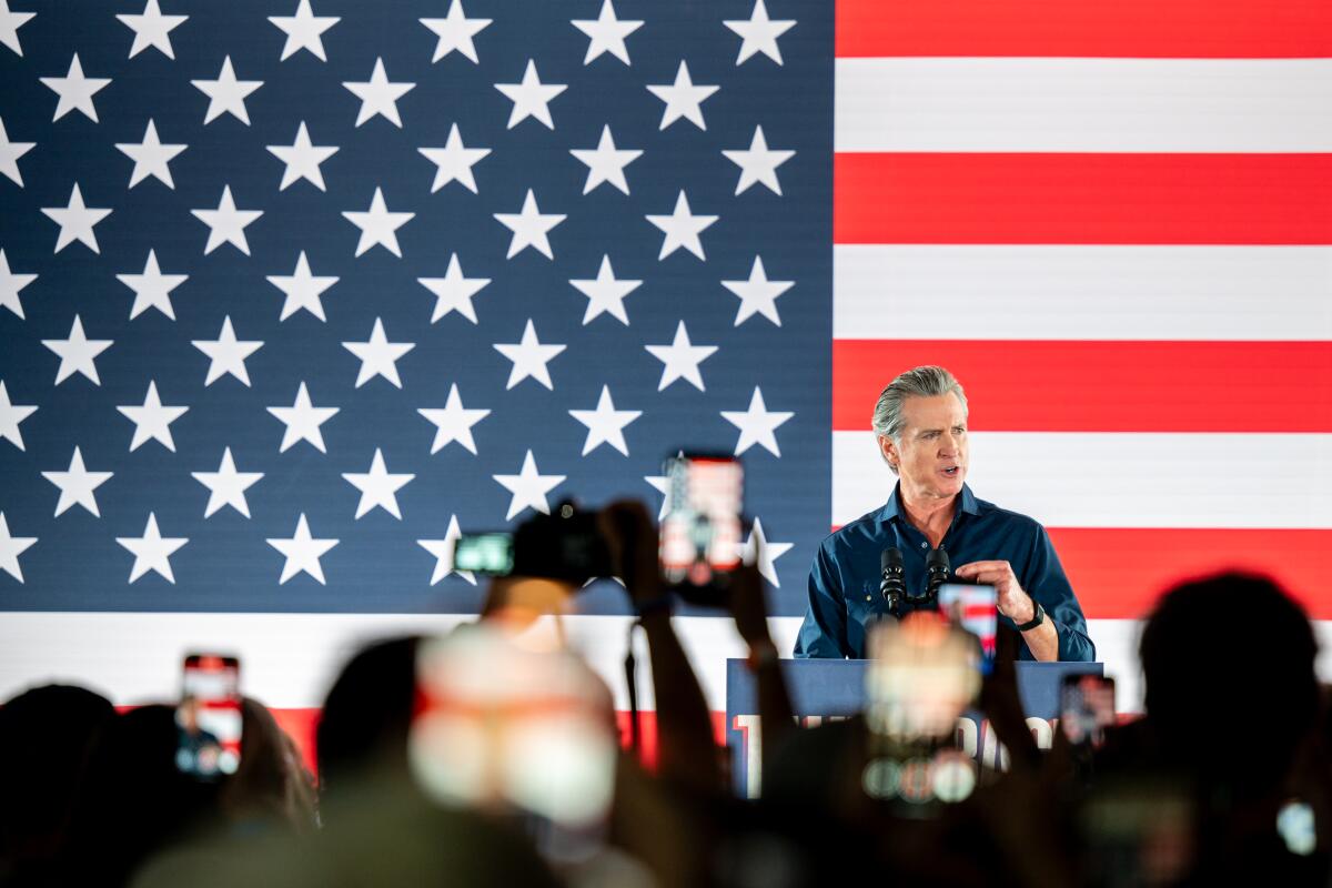 California Gov. Gavin Newsom standing in front of an American flag delivering a speech