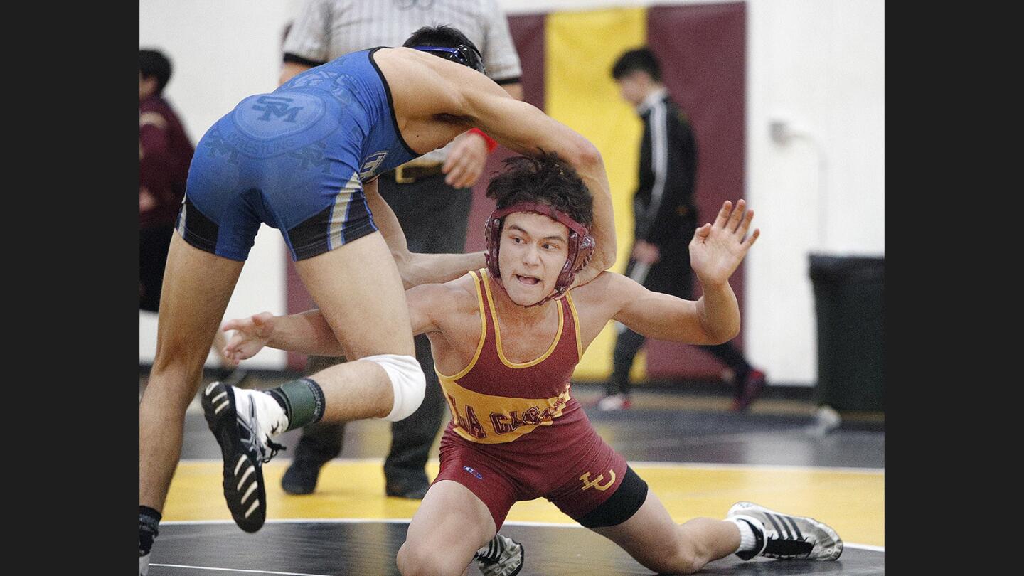 La Canada's Tyler Reese reaches for the leg of San Marino's Bean Perez in the 145-pound match in a season opener of the Rio Hondo League wrestling at La Canada High School on Thursday, January 4, 2018. La Canada won the match 48-30.