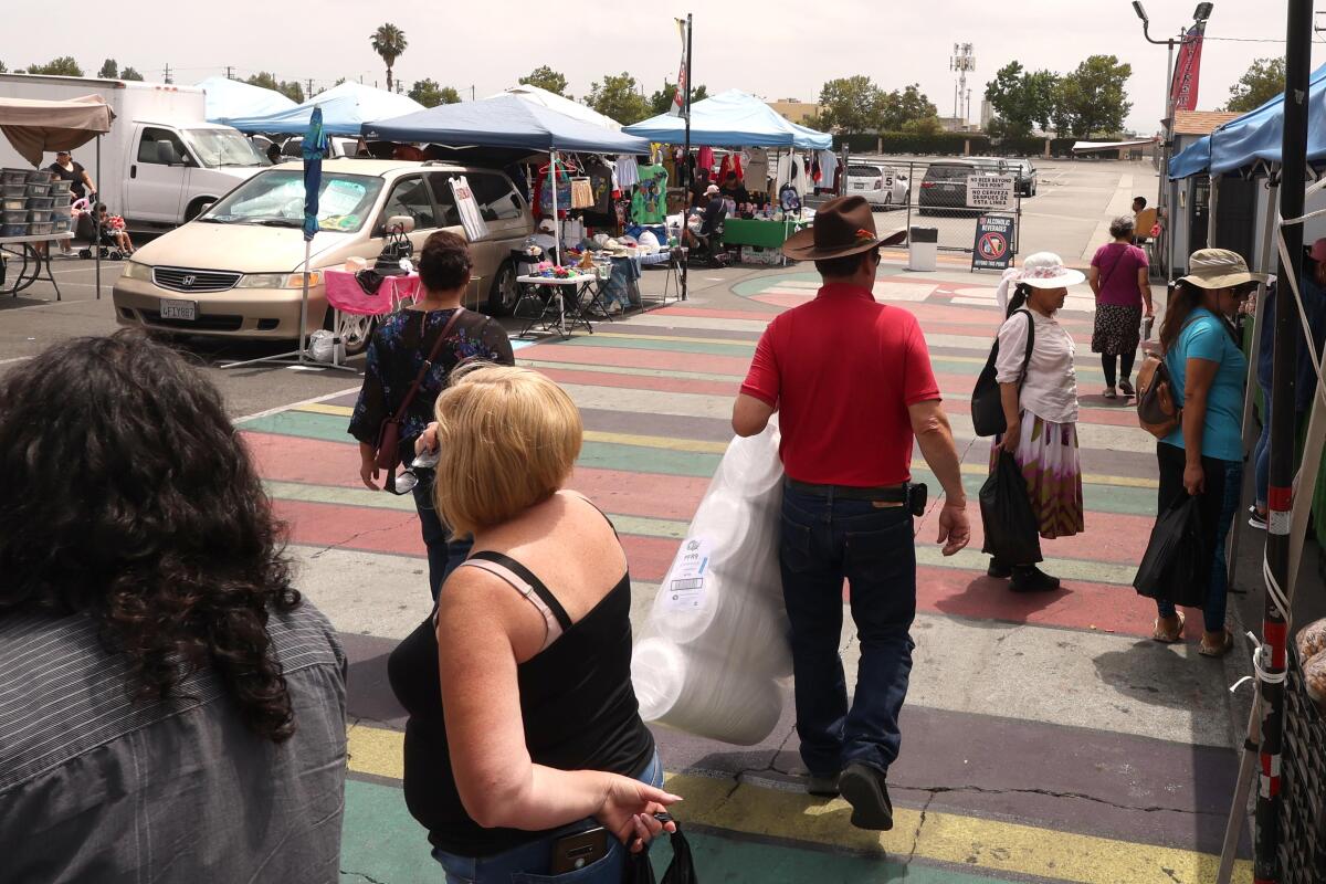 a handful of shoppers walk through the San Fernando Swap Meet