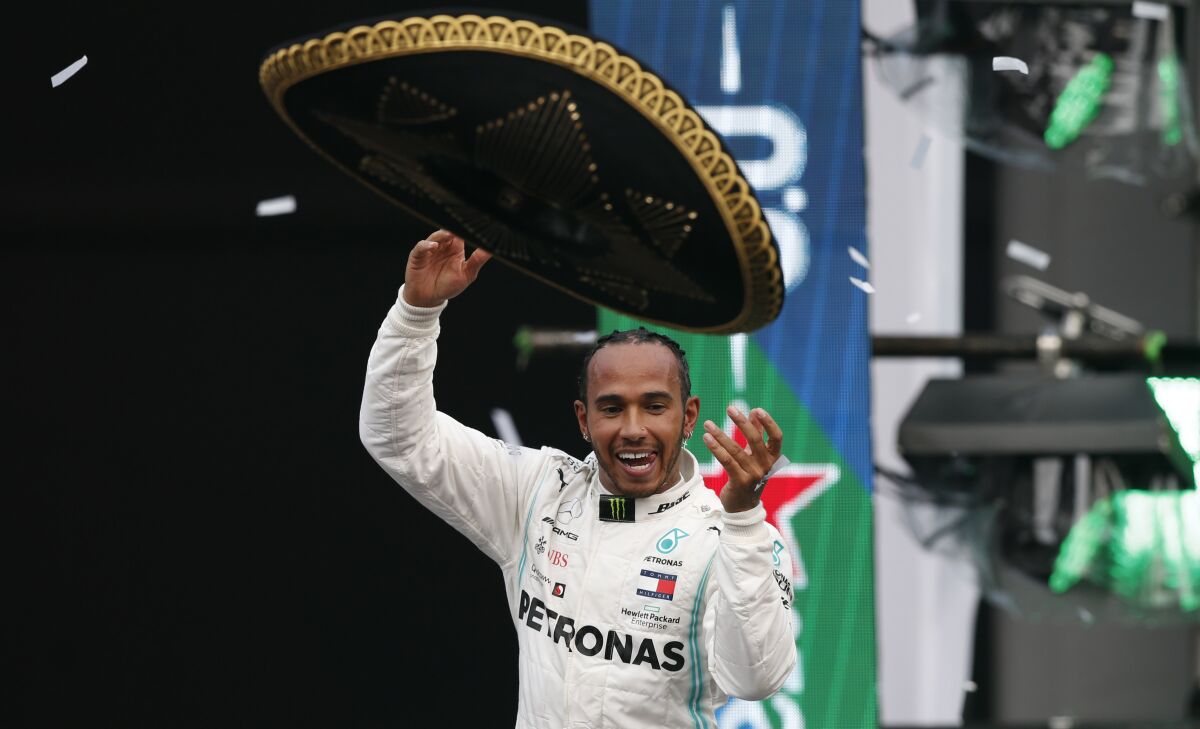 ARCHIVO - En imagen de archivo del domingo 27 de octubre de 2019, el piloto británico Lewis Hamilton, de Mercedes, arroja un sombrero de charro al público mientras festeja su victoria en el Gran Premio de México de la Fórmula Uno, en el autódromo Hermanos Rodríguez de la capital mexicana. (AP Foto/Rebecca Blackwell, archivo)