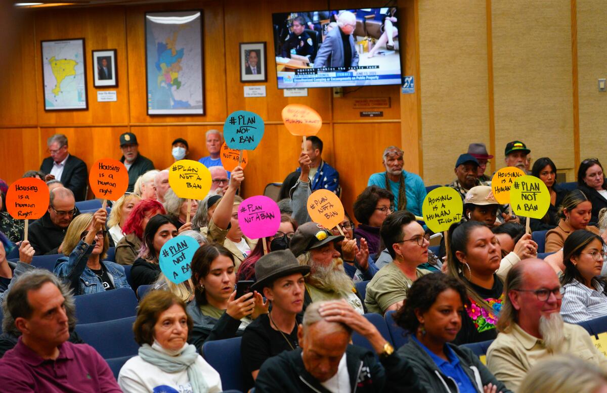 People opposed to a San Diego ordinance containing prohibitions against camping on public property hold signs.
