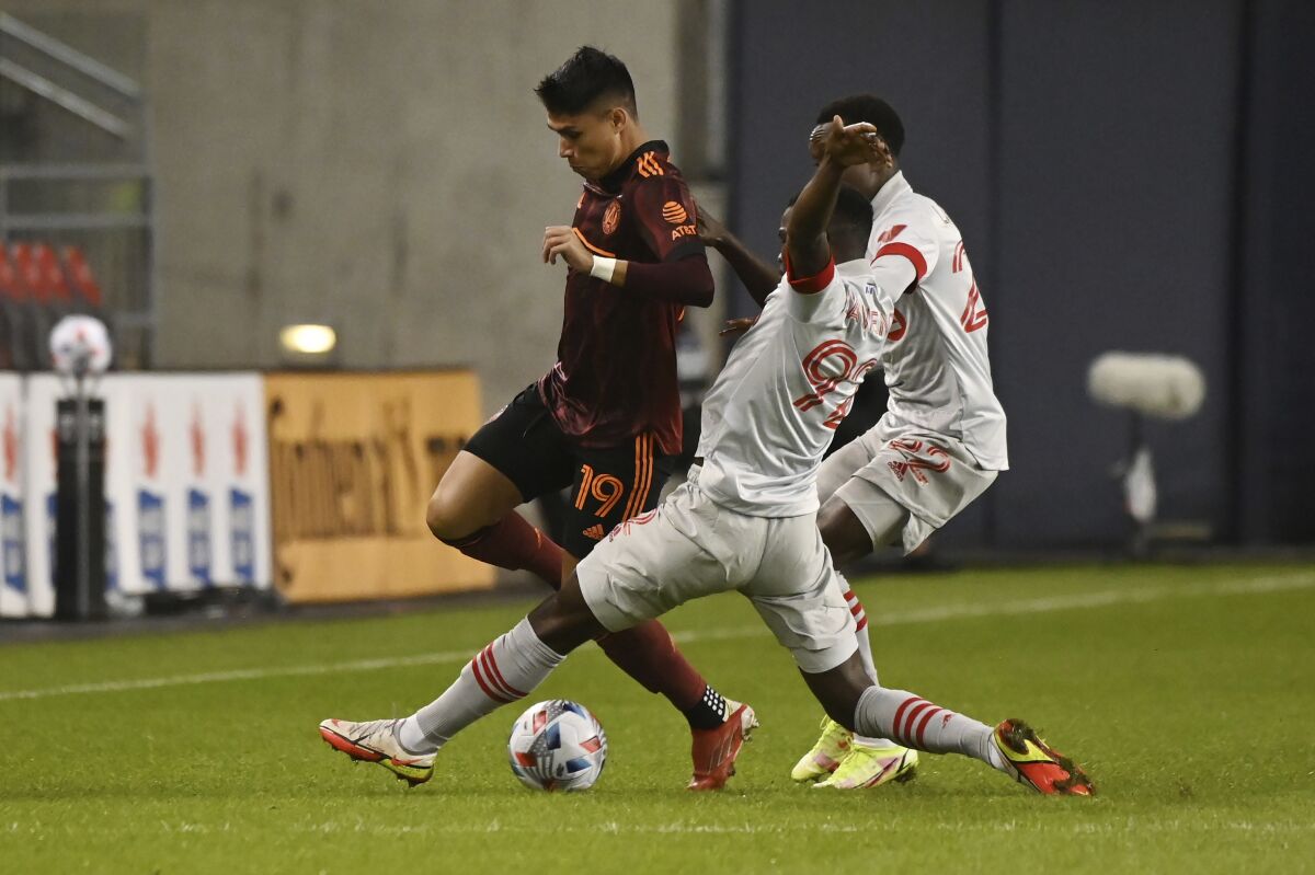 Atlanta United's Luiz Araujo (19) is tackled by Toronto FC's Kemar Lawrence (92) and Richie Laryea (22) during the first half of an MLS soccer match Saturday, Oct. 16, 2021, in Toronto. (Jon Blacker/The Canadian Press via AP)