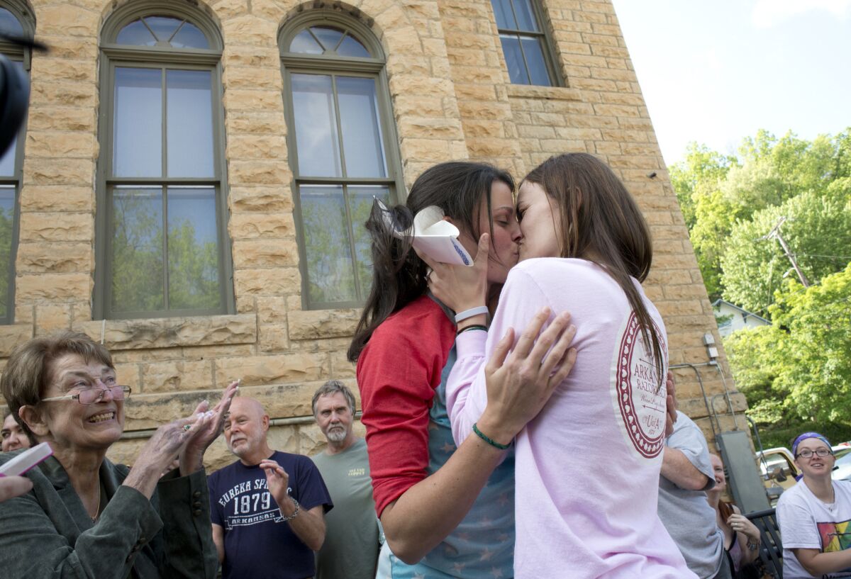 Kristin Seaton, left, and Jennifer Rambo celebrate after becoming the first same-sex couple to be married at the Carroll County Courthouse in Arkansas. Cheryl Maples, far left, the lead attorney who filed a lawsuit challenging the state's ban on gay marriage, looks on.