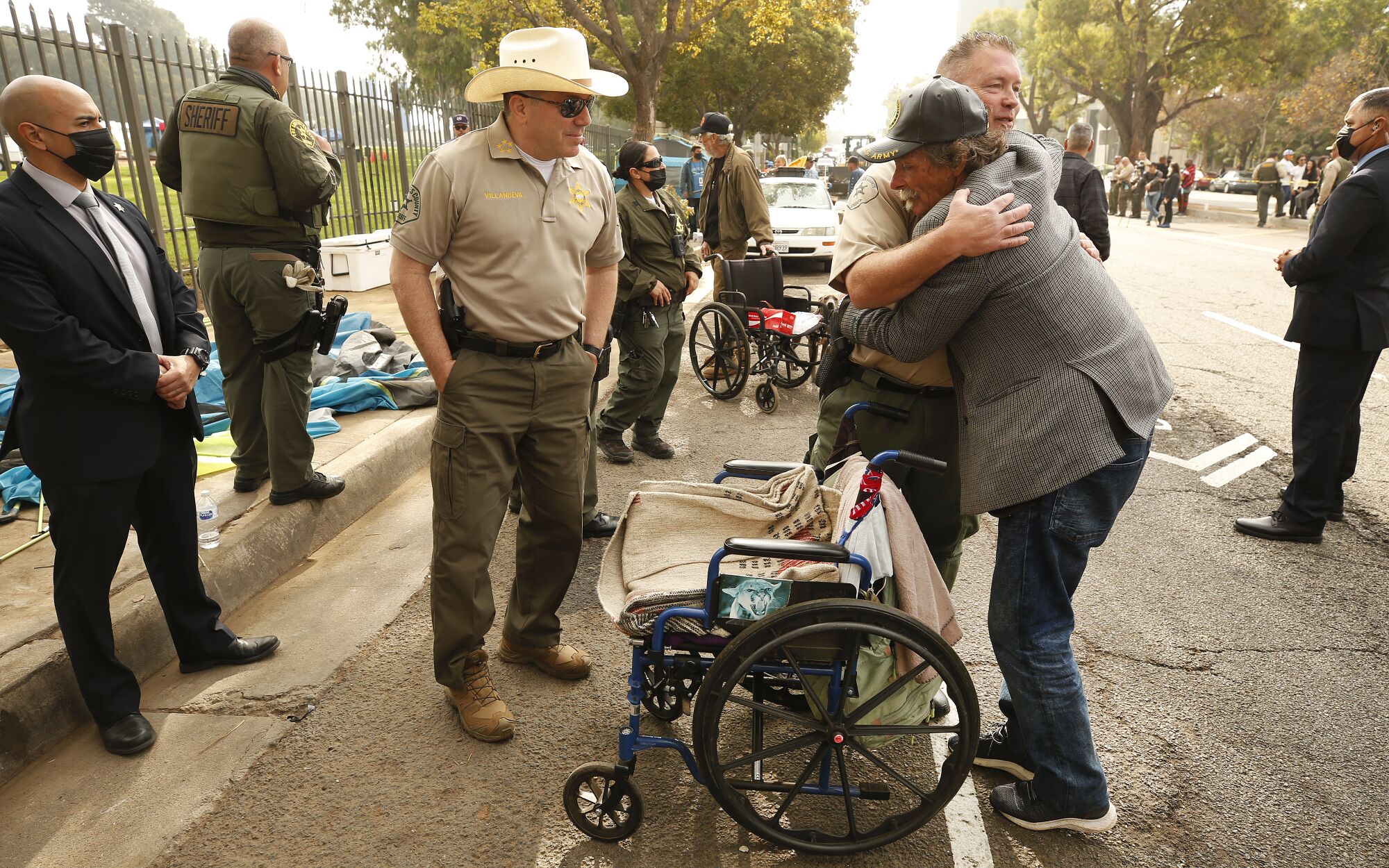 Army veteran Douglas Steven Bue hugs Sheriff's Lt. Jeff Deedrick while others look on