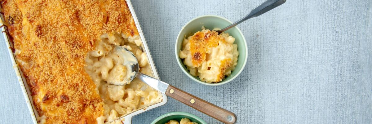 Best ever mac 'n' cheese being spooned from a casserole dish