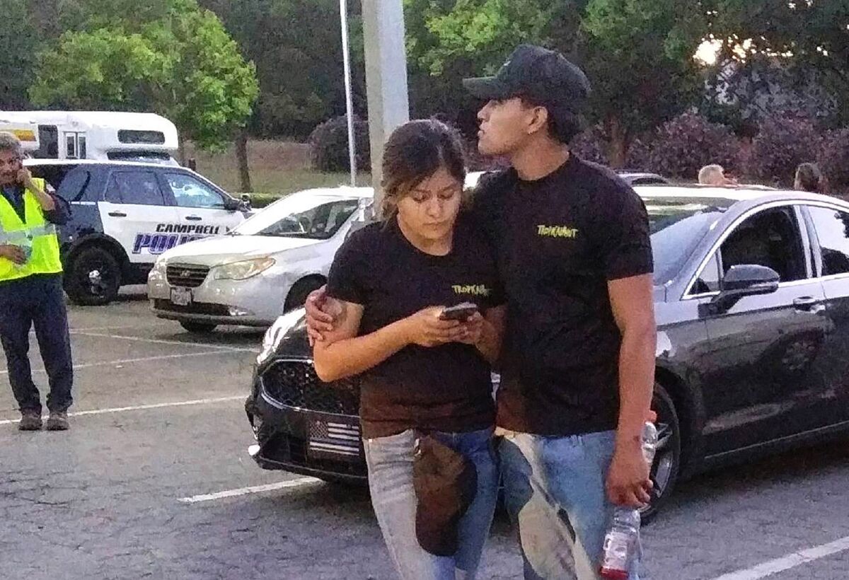 A young couple embrace in a parking lot after a shooting at the Gilroy Garlic Festival.