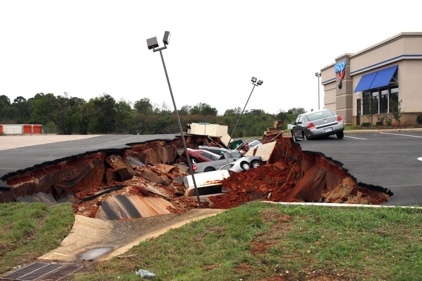 This photo shows vehicles after a cave-in of a restaurant parking lot in Meridian, Miss., Sunday, Nov. 8, 2015. Experts are to begin work Monday seeking to determine the cause of the Saturday collapse, authorities said.