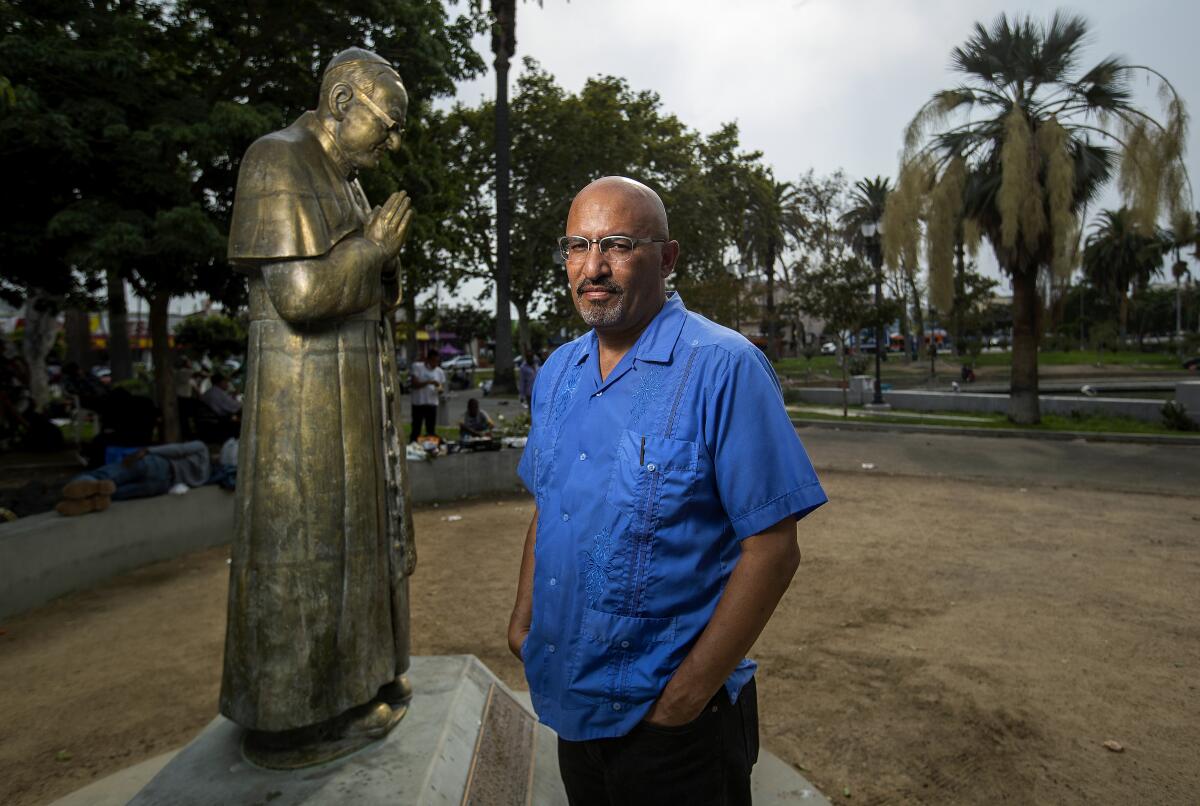 Roberto Lovato next to a statue of Saint Oscar Arnulfo Romero, the former archbishop of El Salvador.