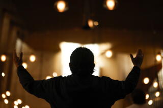 A man lifts his arms in prayer at the Cathedral of Our Lady of the Angels.