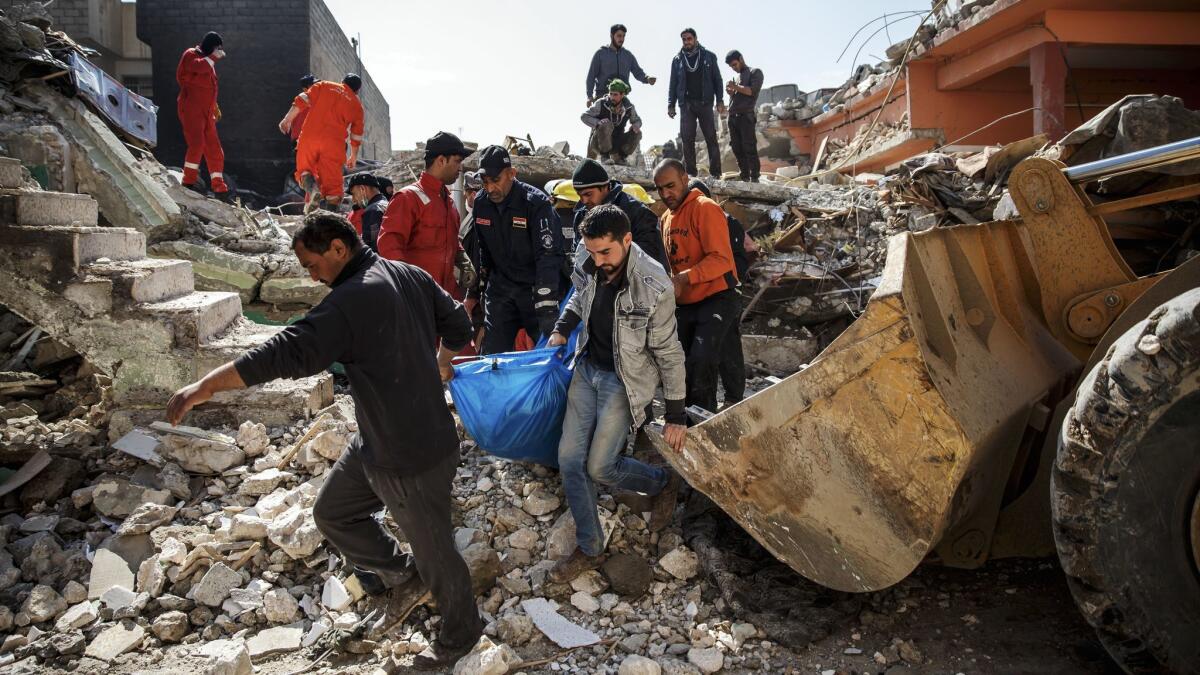 With the help of family members, Iraqi civil defense force members recover a body buried in the rubble of a destroyed home after reported coalition airstrikes in Mosul's Jadidah neighborhood in March 2017.