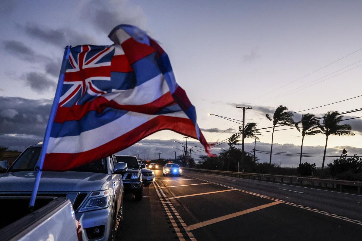 A Hawaiian flag waves in the wind as drivers wait in a line of vehicles to return to Lahaina on Aug. 16. 