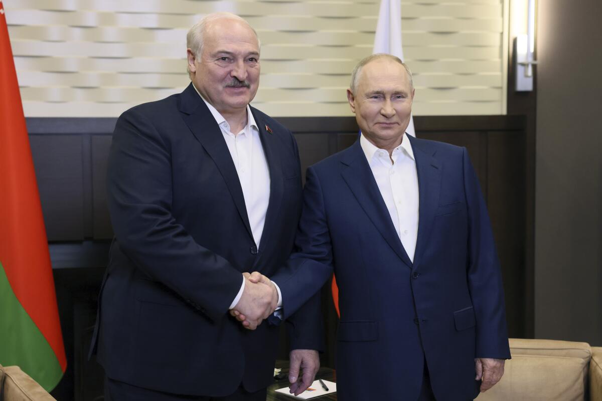 Presidents Lukashenko, left, and Putin shake hands and pose for a photo 