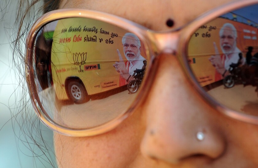 A bus plastered with the image of Indian prime ministerial candidate Narendra Modi is reflected in an onlooker's sunglasses in Ahmedabad, India.