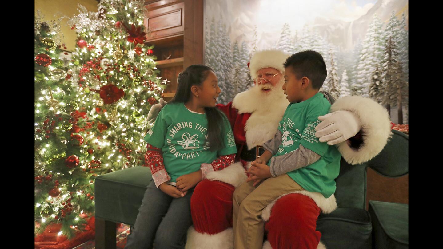 Natalia Hernandez, 10, and her brother Eduardo, 5, speak to Santa Claus during the 11th annual “Sharing the Spirit Holiday Party” at South Coast Plaza on Friday in Costa Mesa. Santa’s Village at South Coast Plaza was transformed into a holiday festival for more than 500 Orange County children without permanent homes, where they enjoyed toys, treats and three hours of holiday fun.