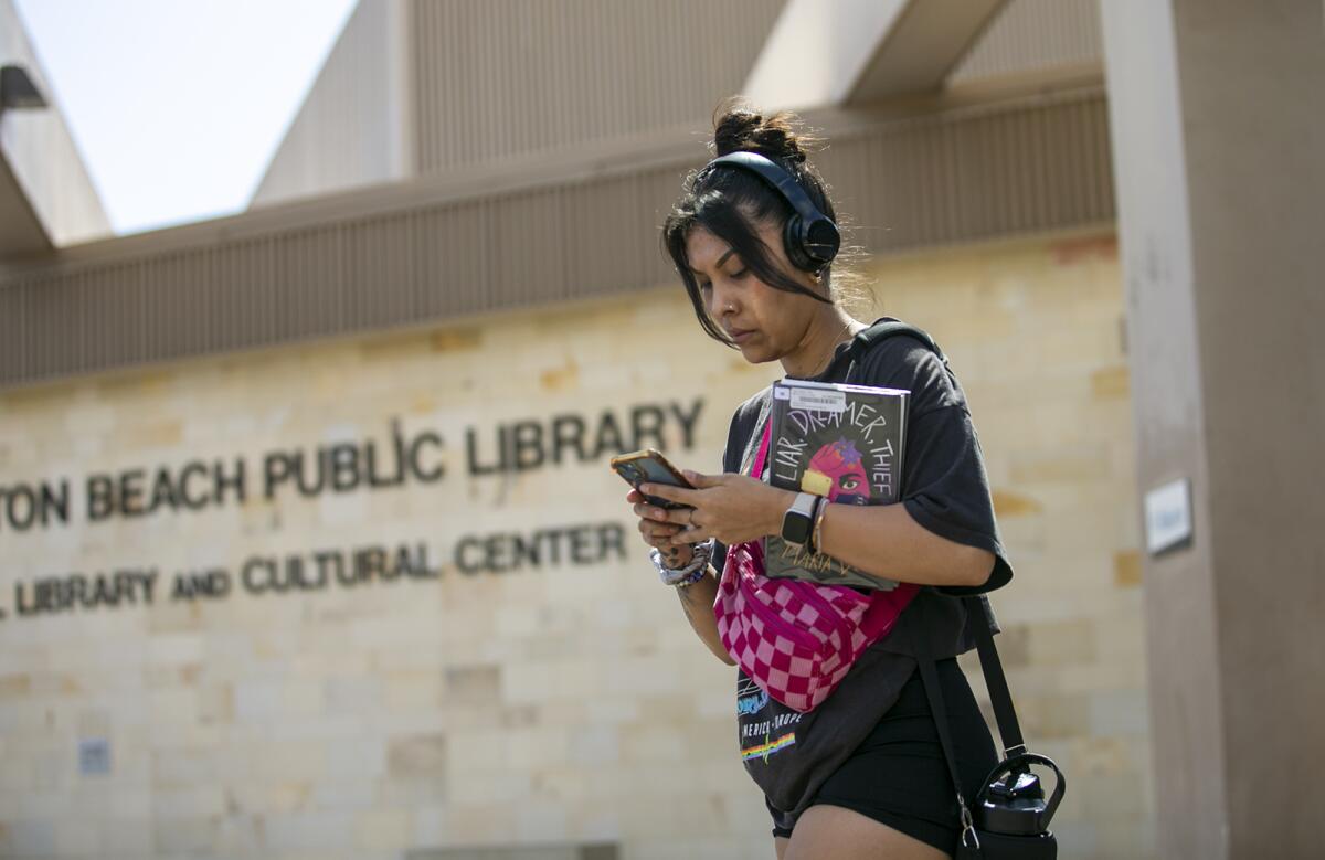 Brenda Tornero walks out of the Huntington Beach Central Library, which reopened on Monday after a two-week closure.