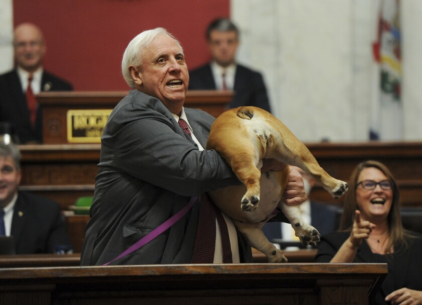 West Virginia Gov. Jim Justice holds up his dog in the House chambers. 
