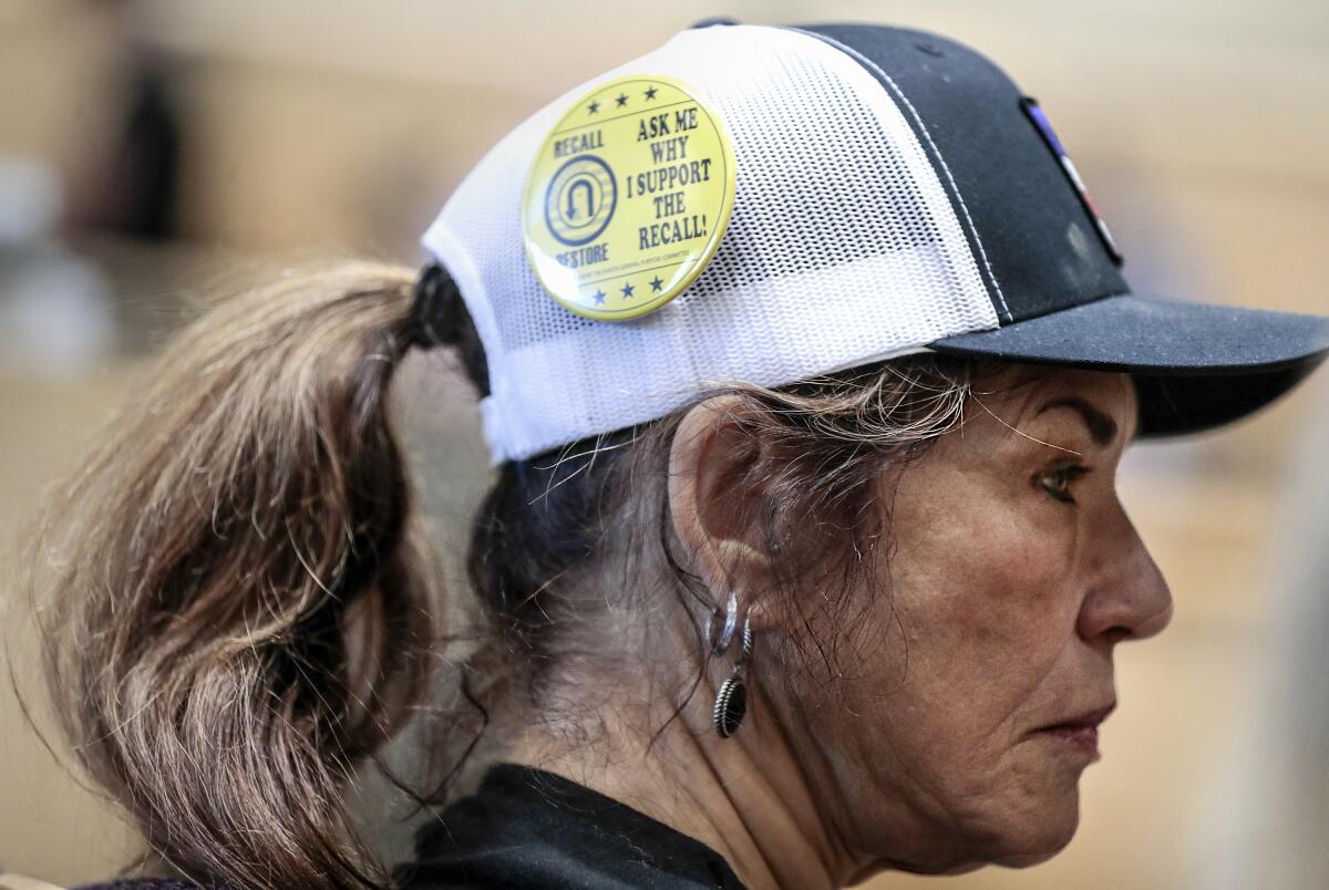 A yellow button on a woman's cap reads, Ask me why I support the recall! 