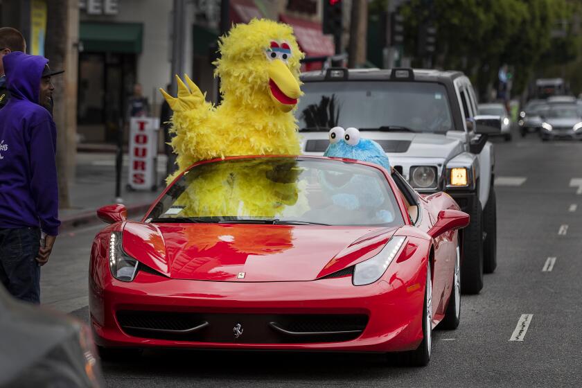 HOLLYWOOD, CA-MAY 9, 2019: People dressed up as Sesame Street characters, Big Bird, left, and Cookie Monster, drive in style, aboard a Ferrari, while traveling along Hollywood Blvd. in Hollywood on May 9, 2019. (Mel Melcon/Los Angeles Times