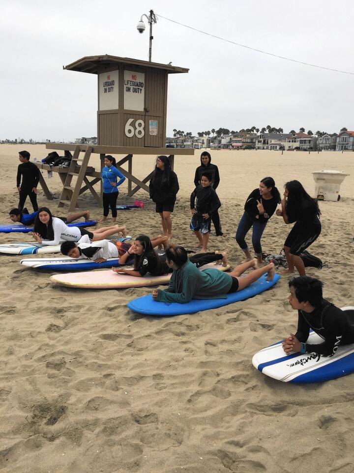 Members of Save Our Youth and participants in the SOY Annual Surf Camp receive on-land instruction from volunteers coaches before they head out to the surf for the first time.