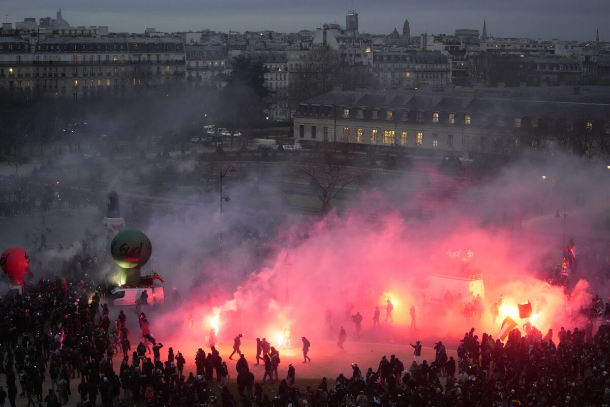 Manifestantes caminan entre el humo provocado por el lanzamiento de bengalas al final de la manifestación contra el plan de retrasar la edad de jubilación en Francia, el martes 31 de enero de 2023 en París. (AP Foto/Thibault Camus)