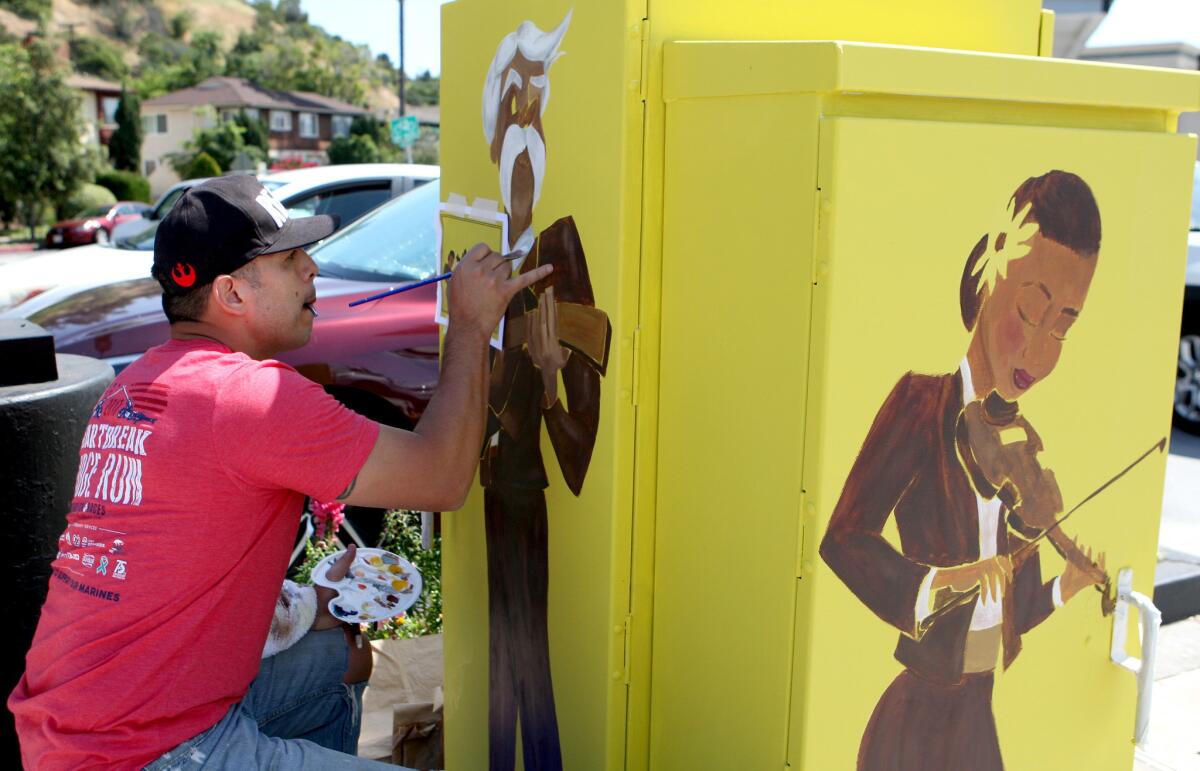 Ruben Espinoza paints mariachi musicians on a utility box at N. Verdugo Road and N. Glendale Avenue in Glendale on Saturday, April 8, 2017.