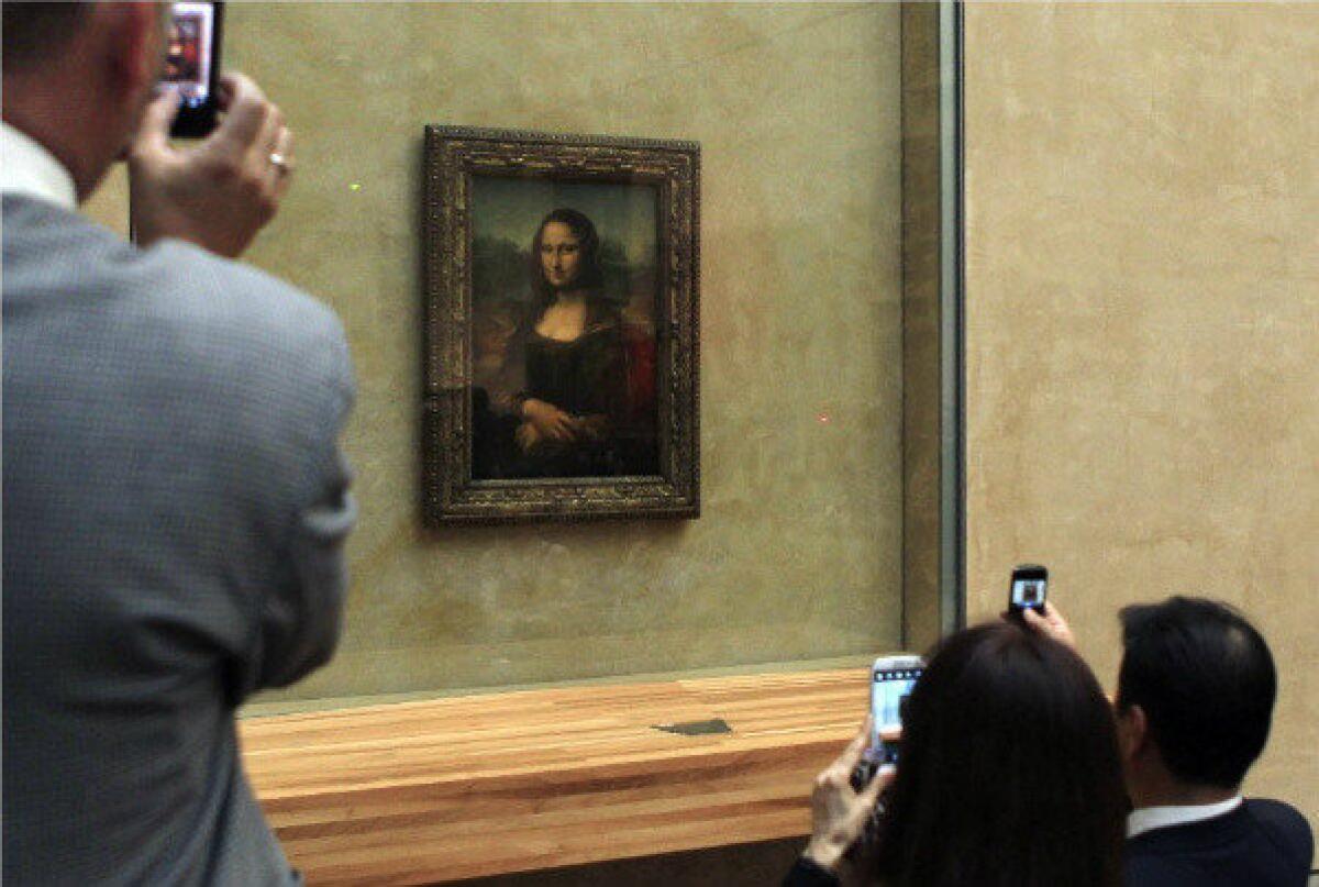 Visitors take photos of the "Mona Lisa" by Leonardo da Vinci at the Musee du Louvre in Paris. The lighting will soon be enhanced.